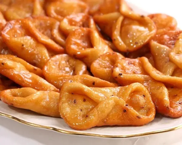 Plato de pestiños antiguos, dorados y brillantes, con un glaseado que los hace irresistibles. Perfectos para acompañar un café.