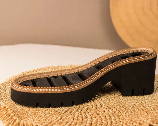 Suela de zapato con plataforma y tacón grueso, elaborada con caucho natural y detalles de cuero.