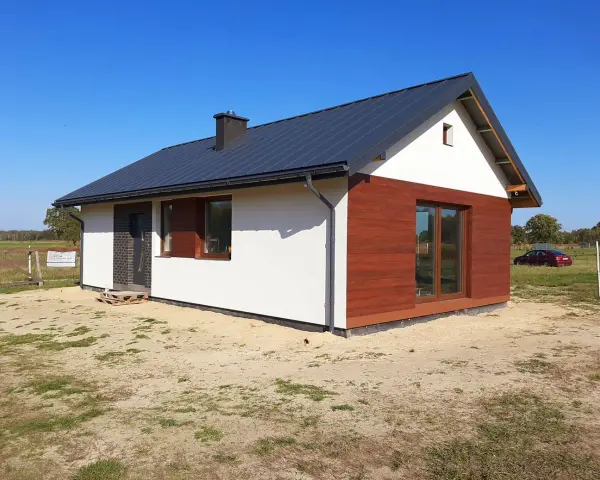 Nowy, nowoczesny dom do 70m2 z drewnianą elewacją i dużymi oknami, gotowy na przyjęcie mieszkańców.