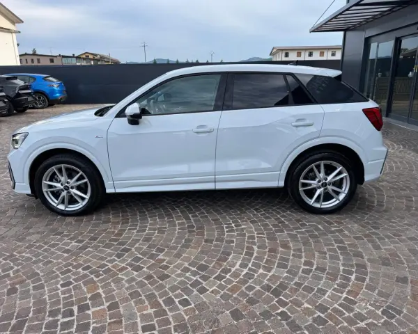 Audi Q2 bianca parcheggiata su pavé. Controlla la pressione pneumatici per un viaggio sicuro.
