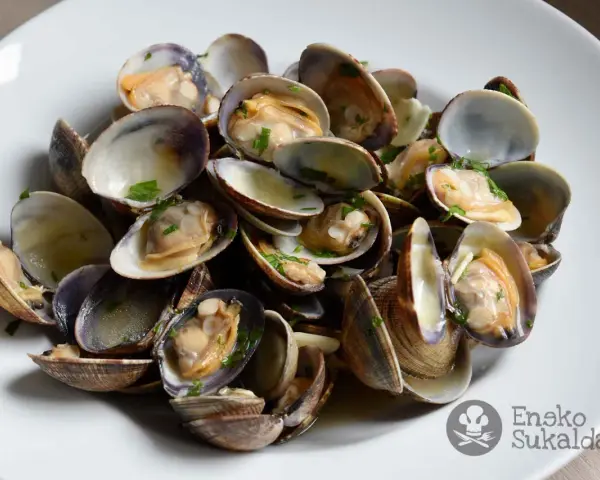 Un plato de almejas a la marinera, jugosas y recién cocinadas, con perejil picado.