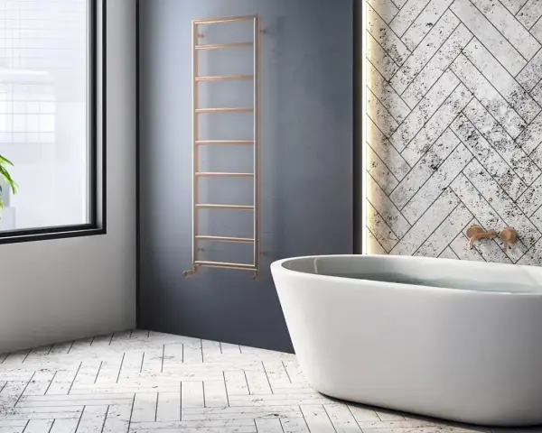 Radiador de agua vertical de cobre, un ejemplo de tipos de radiadores de agua, junto a una bañera y una planta.