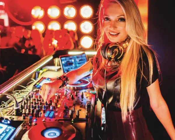 Une dj femme connue aux platines, mixant dans une ambiance club avec des lumières rouges.