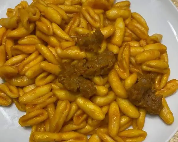 Un piatto invitante di gnocchetti alla campidanese, conditi con un sugo ricco e pezzetti di carne saporita.
