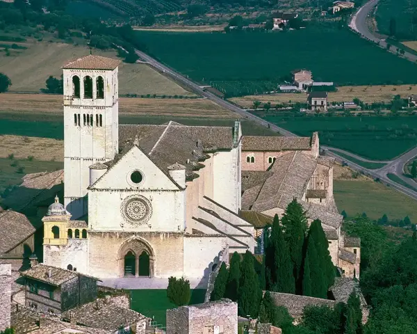 Basilica of Saint Francis of Assisi, a stunning example of Italian monasteries, with its iconic bell tower and rose window, nestled in a verdant landscape.