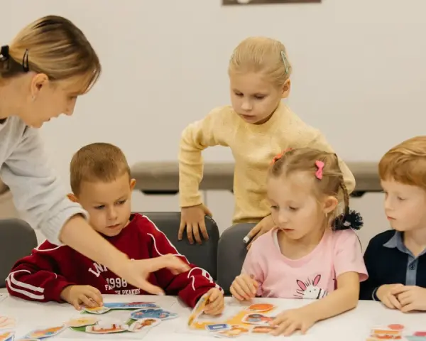 Nauczycielka pomaga dzieciom układać obrazki. Czy przedszkole może wypisać dziecko? Dzieci uczą się przez zabawę.