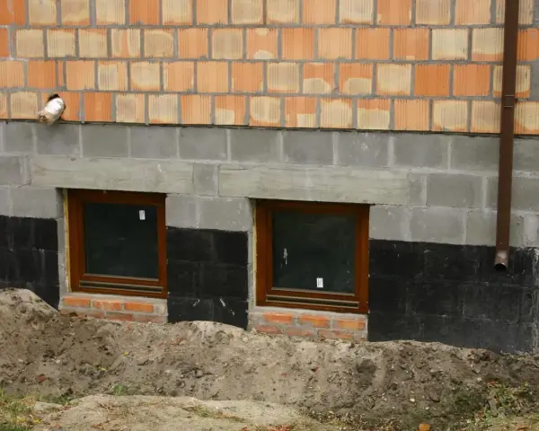 Fundamenty starego domu wymagają wzmocnienia. Widoczne okna piwniczne, izolacja i nowe mury świadczą o pracach.