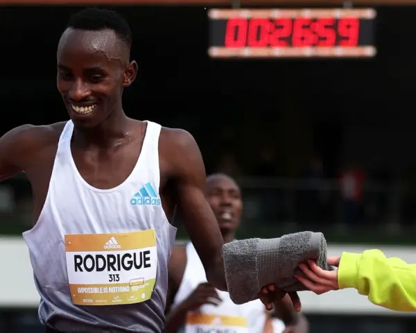 Atleta sonriente recibe toalla en una carrera de Madrid vintage. El marcador digital muestra 00:26:59.