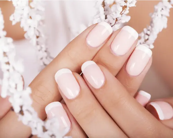 Mani curate con unghie french impeccabili, incorniciate da delicati fiori bianchi.