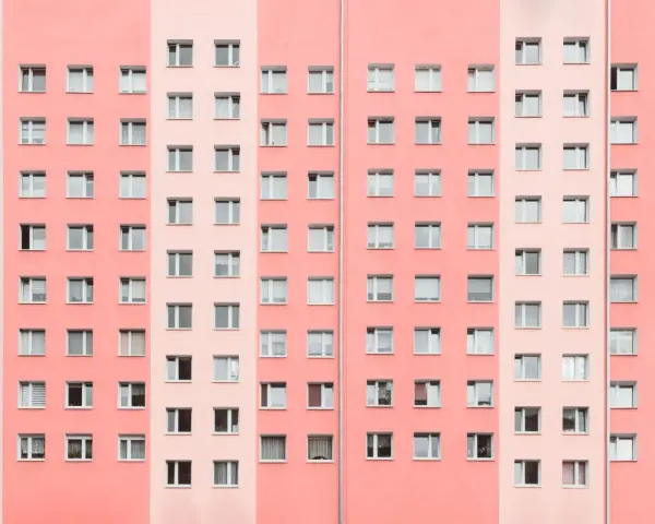 Pasteloza w architekturze: fasada bloku mieszkalnego w odcieniach różu i brzoskwini, z rzędami okien.