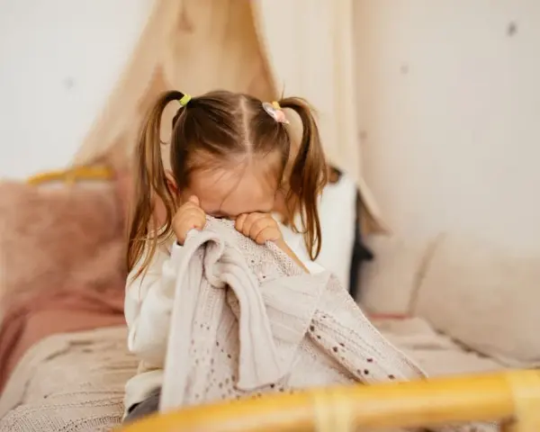 Kleines Kind mit Zöpfen versteckt sich unter einer Decke, weil es Angst vor Monstern hat.
