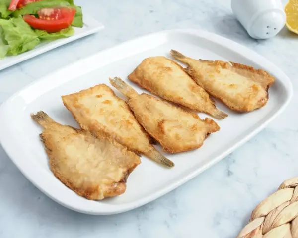 Cinco acedias fritas doradas y crujientes en una bandeja blanca, listas para disfrutar.