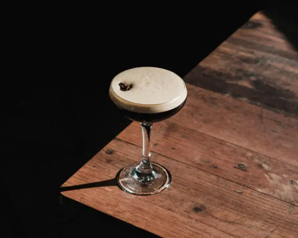 Espresso Martini przepis: elegancki koktajl z pianką i ziarnem kawy na drewnianym blacie.