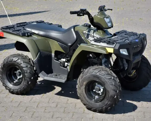 Zielony quad Polaris Sportsman 300 na kostce brukowej.