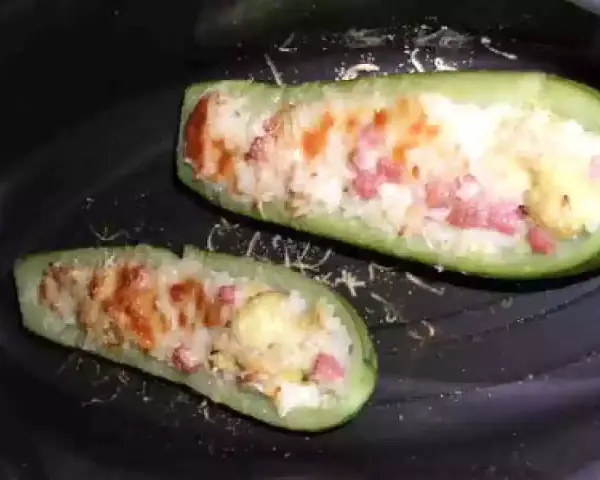 Zucchine ripiene di riso, condite con pomodoro e formaggio, pronte per essere gustate.