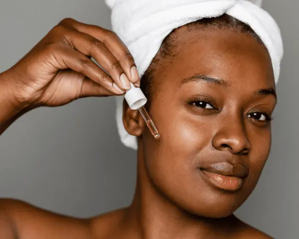 A woman applies a serum with peptides for acne, a step in her skincare routine.
