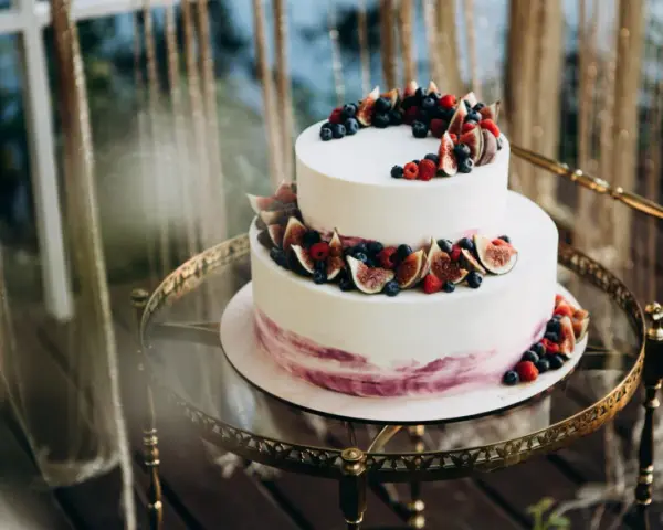 Elegancki tort piętrowy na 40 osób, ozdobiony świeżymi figami, borówkami i malinami. Idealny na wyjątkowe przyjęcie.