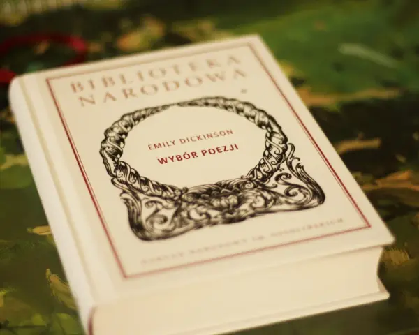 Biała księga z napisem "Emily Dickinson Wybór Poezji" w ozdobnej ramce.