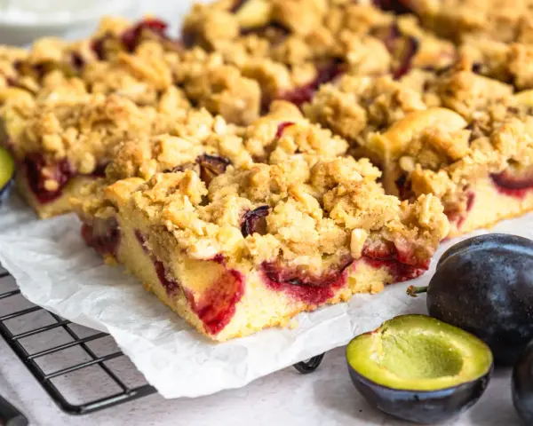 Saftiger Zwetschgenkuchen mit Streuseln, frisch gebacken und bereit zum Genießen. Daneben liegen frische Zwetschgen.