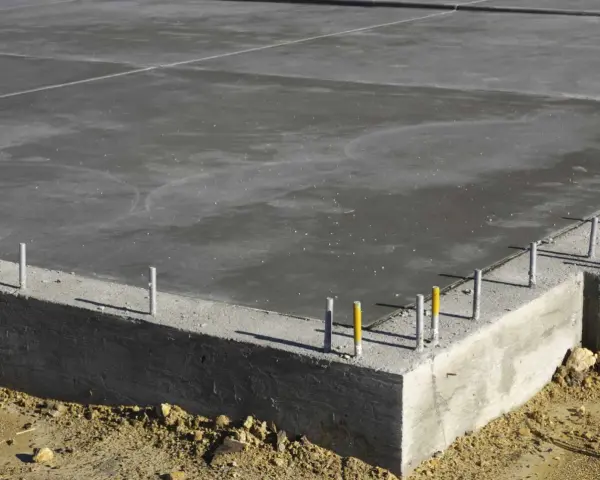 Dalle de béton fraîchement coulée, montrant la base d'une fondation et l'épaisseur de la semelle en béton.