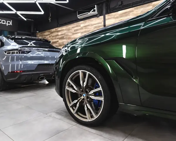 Lśniące, zielone BMW i szare Porsche w garażu. To efekt profesjonalnego auto detailingu, który przywraca blask lakierowi i dba o każdy detal pojazdu.