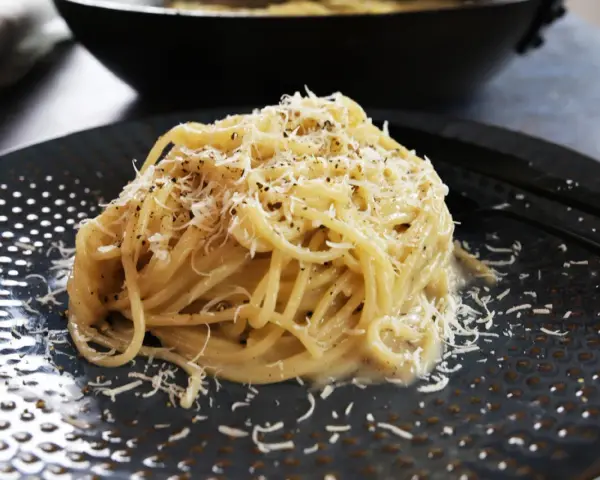 Pyszne spaghetti Cacio e Pepe, posypane startym parmezanem i świeżo mielonym pieprzem. Idealne na szybki obiad.