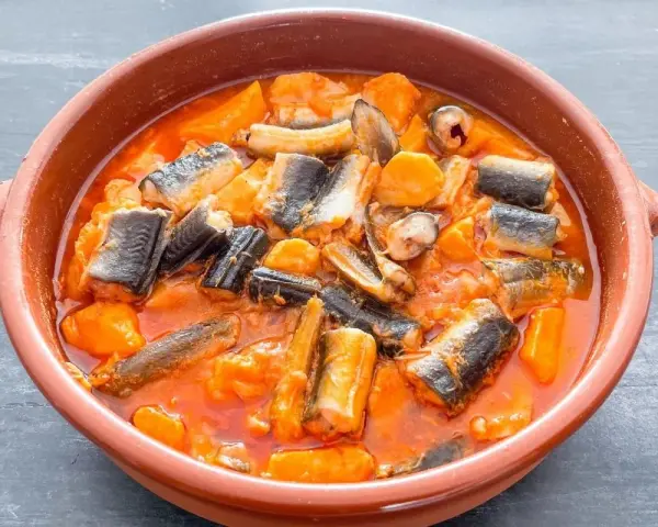 Un cuenco de barro con un sabroso all i pebre, un guiso tradicional de anguila y patatas en salsa roja.
