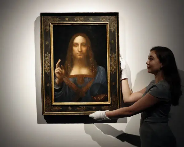 En kvinna med vita handskar hanterar den berömda tavlan "Salvator Mundi", ibland kallad "Mona Lisa tavla" av misstag.
