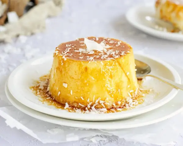 Delicioso flan de coco, cubierto con caramelo dorado y coco rallado, listo para disfrutar.