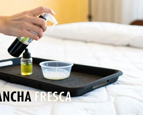 Mano rociando limpiador sobre una bandeja con líquidos para limpiar colchon.