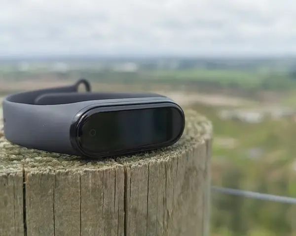 Czarny Mi Band 4 na drewnianym słupku, idealny do śledzenia aktywności. To najlepsza aplikacja do Mi Band 4 dla aktywnych osób.