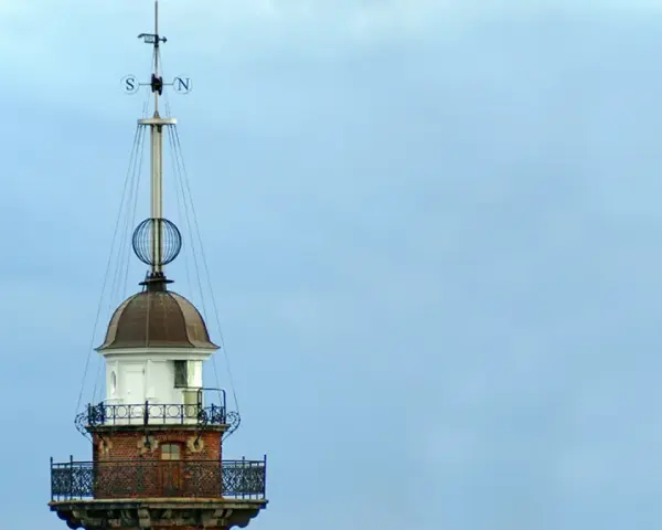 Szczyt latarni morskiej w Gdańsku z wiatrowskazem i kulistą ozdobą.