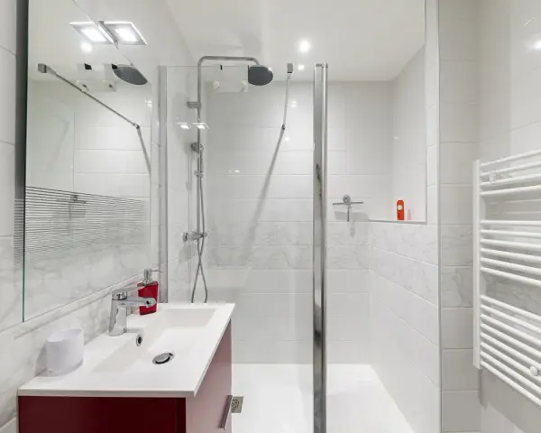 Salle de bain moderne, prête pour la prochaine étape de rénovation. Douche, lavabo et sèche-serviettes blancs.
