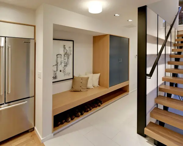 Ideas para decorar un pasillo interior: un banco de madera con almacenamiento, cuadros y una escalera moderna.