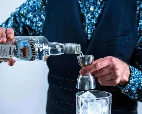 Barman nalewa Żubrówkę do jiggera. Idealna wódka na wesele, by stworzyć niezapomniane drinki.