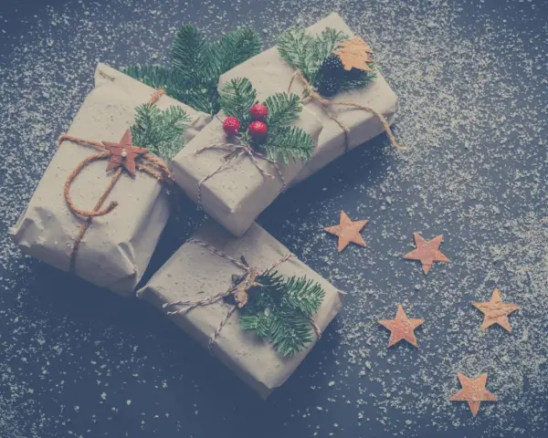 Julklappar inslagna i brunt papper med granris och stjärnor. Perfekta julkort idéer för en mysig julkänsla.