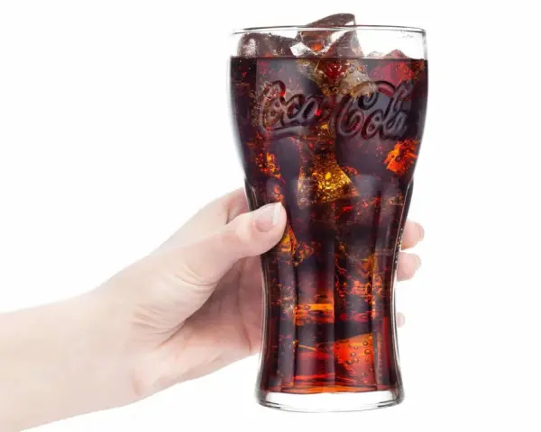 Hand hält Glas mit eiskalter Cola. Frage: Ist Cola in der Schwangerschaft erlaubt?