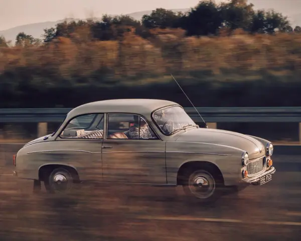Klasyczny Syrena 105 na drodze, uchwycony w dynamicznym ujęciu panning shot.