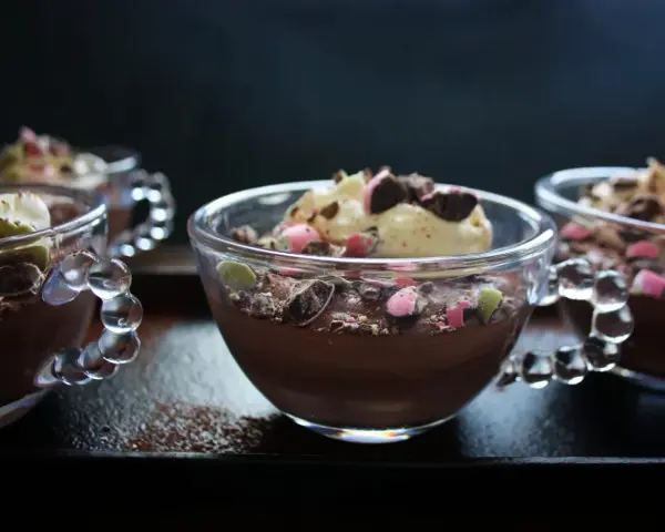 Chokladmousse recept i små glasbägare, toppad med grädde och krossad choklad. En perfekt dessert!
