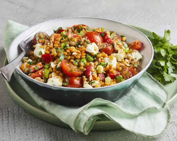 Ein bunter rote Linsen Salat mit Tomaten, Mozzarella und Nüssen, appetitlich angerichtet.
