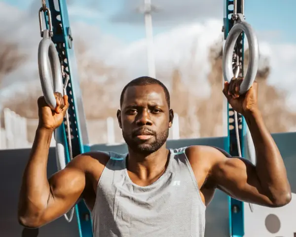 Un homme musclé s'entraîne avec des anneaux de street workout maison.