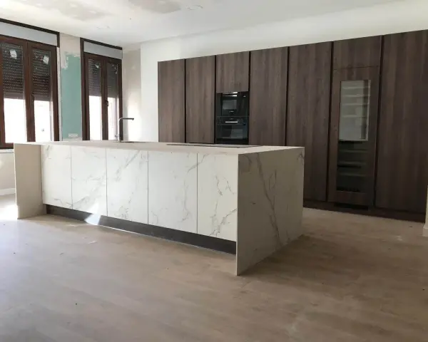 Isla de cocina moderna con encimera de mármol y armarios oscuros. Se aprecian las medidas de los muebles de cocina en el diseño.