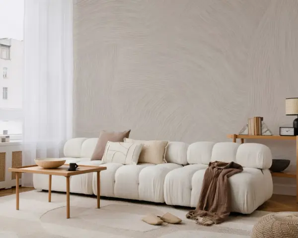 Minimalistyczny salon z sofą, stolikiem i lampą. Subtelne wzory na ścianie i dywanie podkreślają różnicę między stylem skandynawskim a japandi w oprawie eventu.