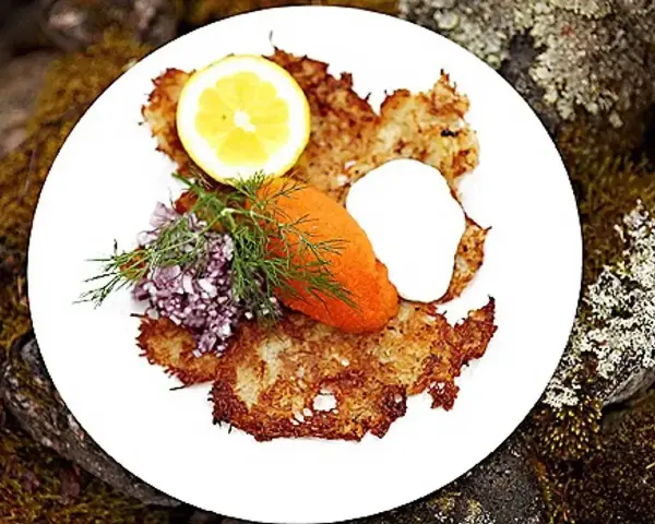 En tallrik med krispiga rårakor, serverade med rom, gräddfil, dill, rödlök och citron. Ett härligt råraka recept!