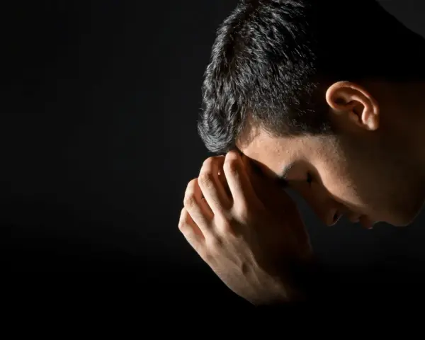A man bows his head in prayer, hands clasped, reflecting the repentance meaning in the bible.