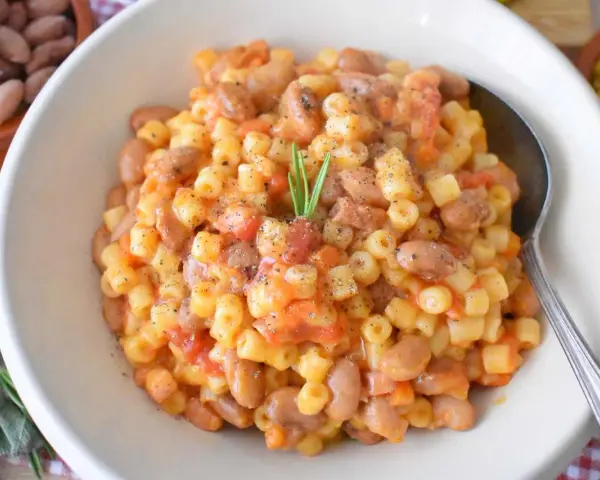 Pyszne danie Pasta e Fagioli przepis. Makaron z fasolą i pomidorami, doprawione pieprzem i gałązką rozmarynu.