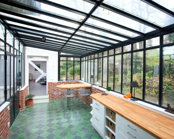 Un'idea per ampliare la cucina nella veranda: un ambiente luminoso con bancone in legno, zona pranzo e vista sul giardino.