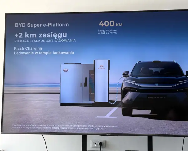 Czarny samochód elektryczny BYD Sealion 8 podłączony do stacji ładowania Flash Charging.