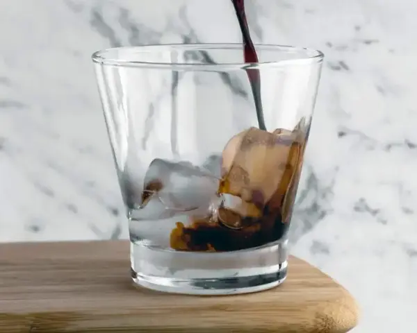 Kall kaffedrink hälls i ett glas med is.