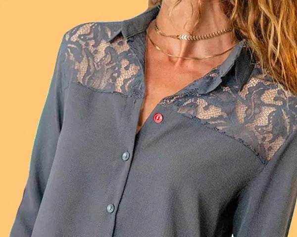 Chemise grise avec empiècements en dentelle sur les épaules. Le boutonnière fille est sur le côté gauche.